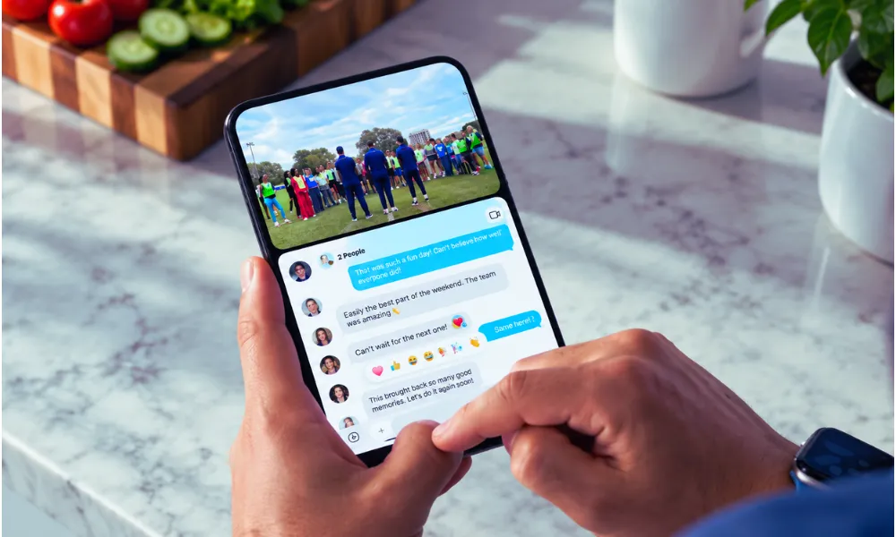 Hand holding an unfolded foldable smartphone displaying apps and widgets.